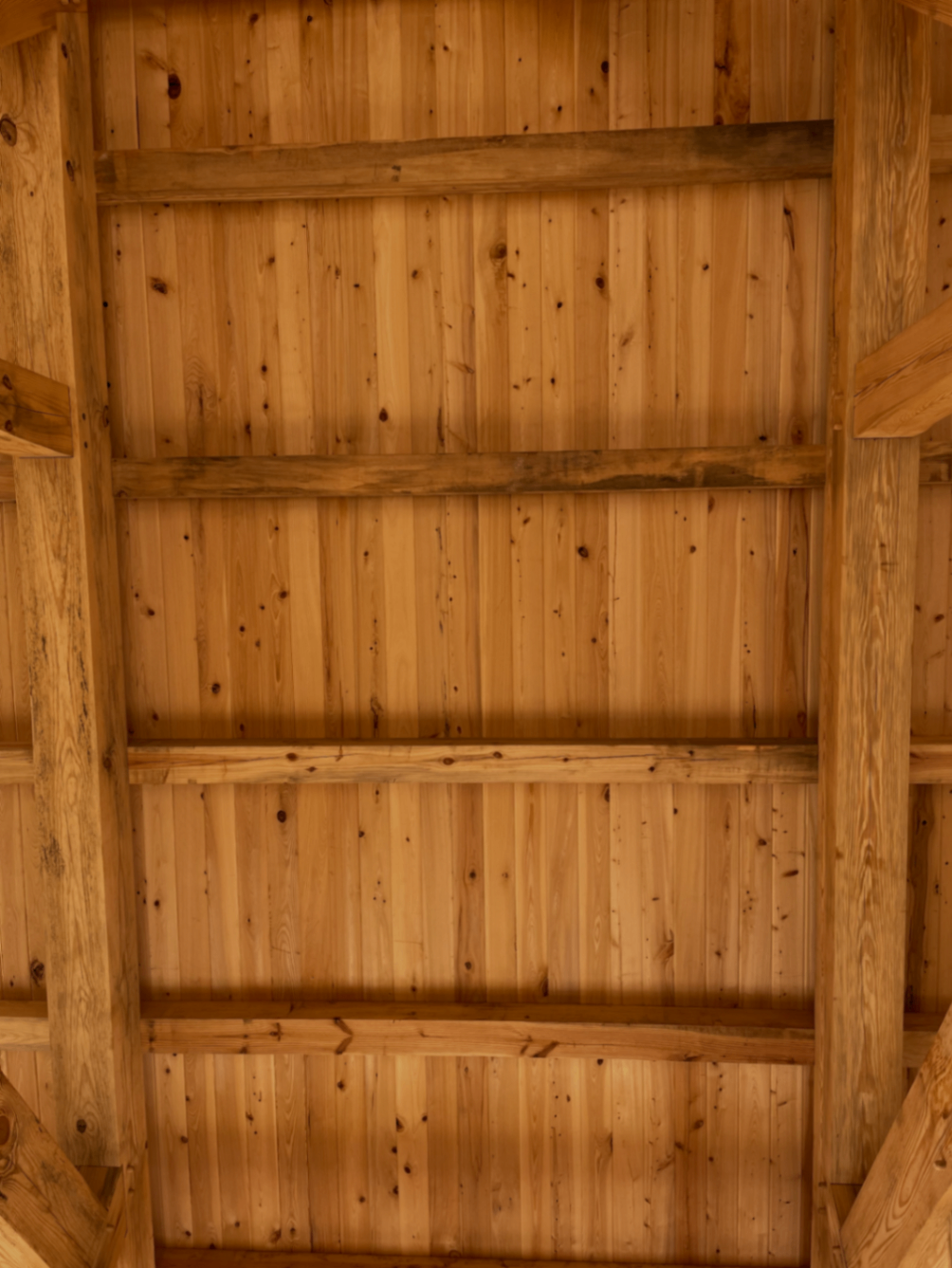 Timber-frame ceiling panel with warm wood boards and purlins