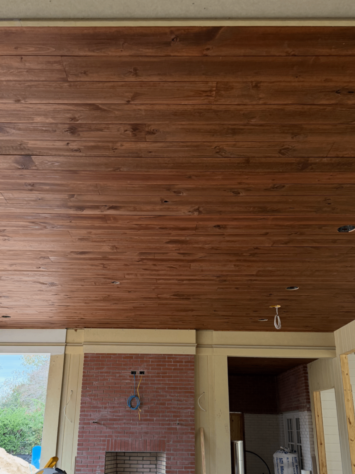 Large finished wood ceiling over a brick fireplace